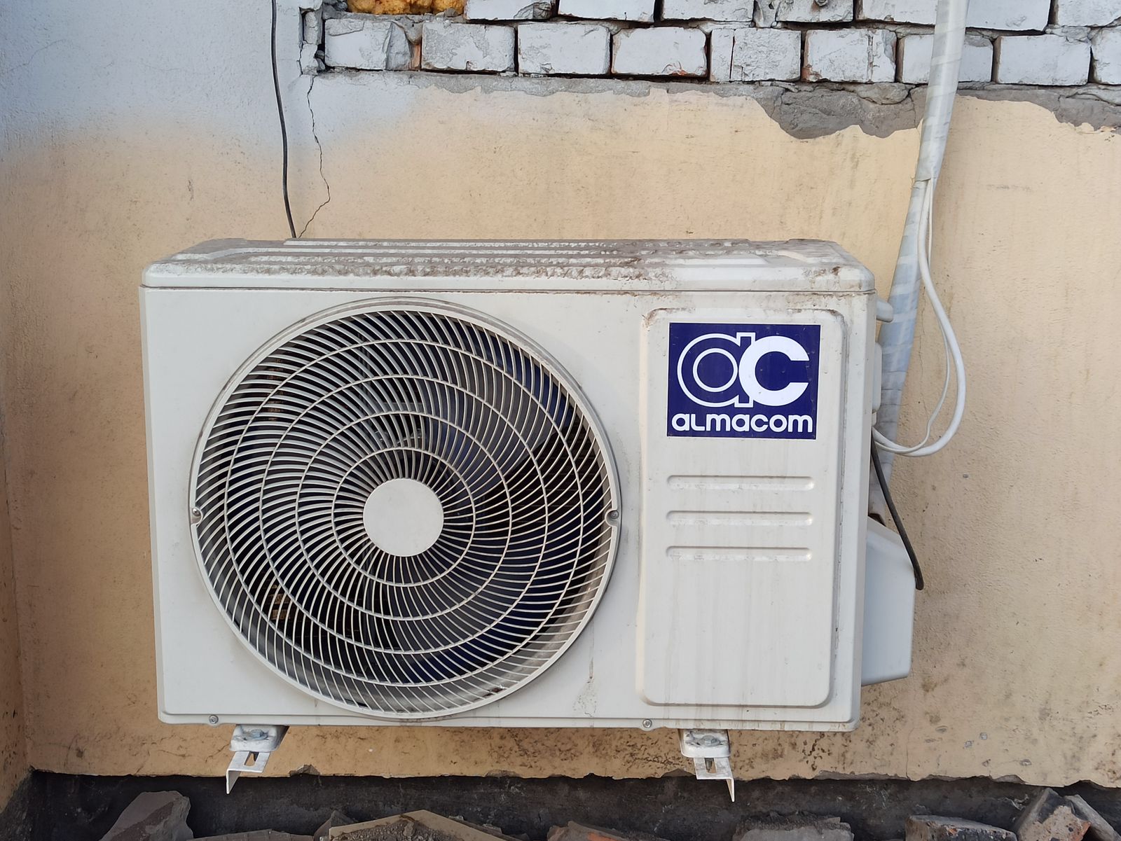 Outdoor air-conditioning condenser with a visible circular fan and housing.